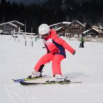 enfant sur une paire de ski qui apprend à s'arrêter sur une descente enneigée