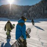 groupe de skieurs en snowboard marchant dans la neige vers la montagne