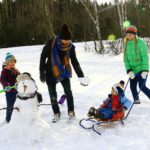 famille dans la neige construisant un bonhomme de neige