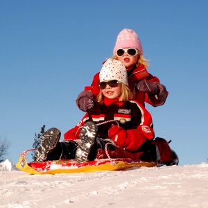 enfants sur une luge en haut d'une descente d'une piste de jeu en hivers